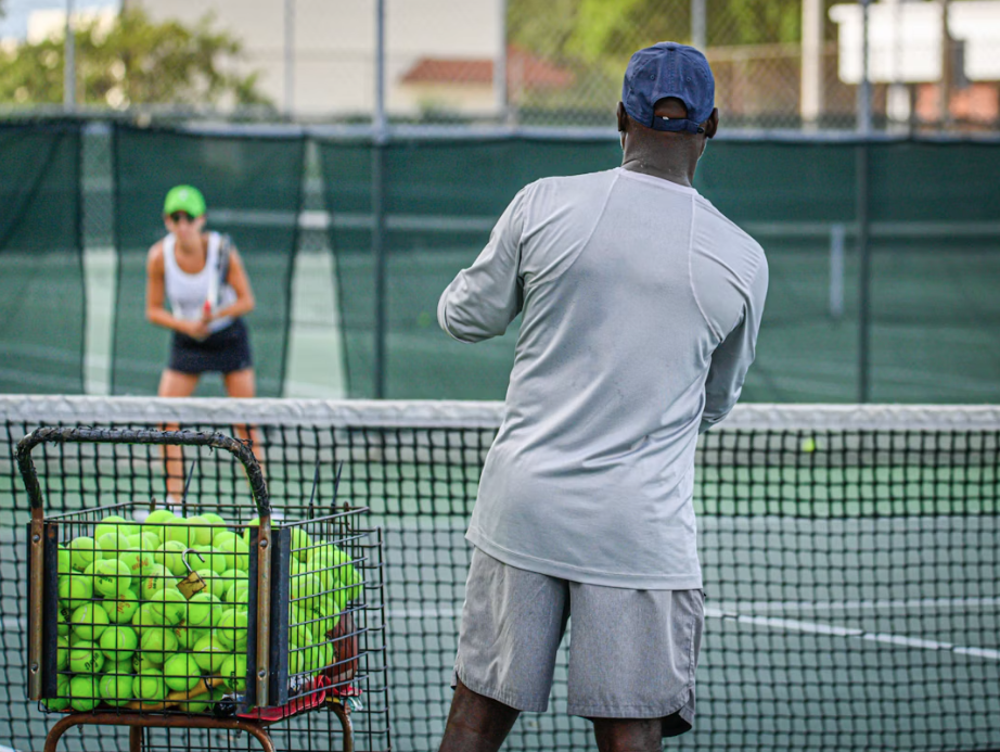 man teaching a lady tennis outside